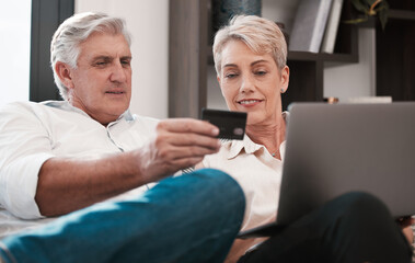 Obraz premium its strange you never knew. Shot of a mature couple using a laptop and paying with a credit card at home together.