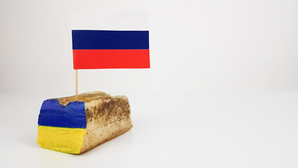 the Russian flag is stuck in the national dish of Ukraine lard. image of the Ukrainian flag on...