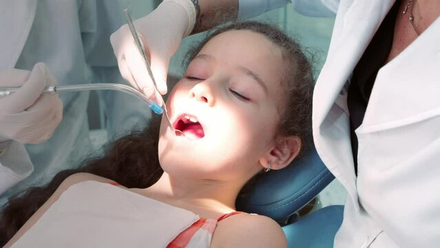 Dentist in the dental office, Woman Dentist Treating Teeth to little girl child Patient in Clinic. Female Professional Doctor Stomatologist at Work. Concept Dental Check Up.