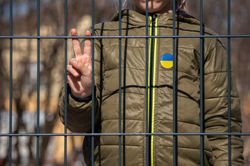 Girl child Ukraine refugee behind a metal fence. Social problem of war migrants.