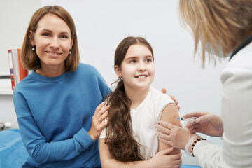 Smiling little girl getting vaccine injection in clinic