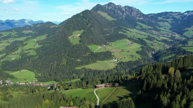 Drone shot of mountain landscape in summer, with scattered Austrian farmhouses and alps. Vacation in Alpbach, Tyrol, Austria.