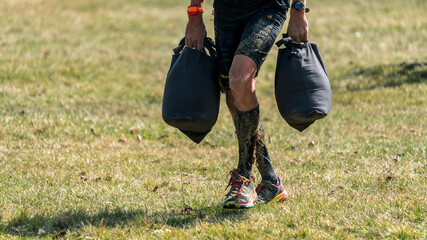 Cutout of an athlete carrying two heavy sand bags at an obstacle course race