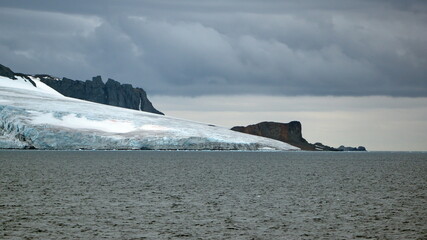Glacier meeting the Southern Ocean at the base of a rugged mountain in Antarctica
