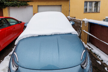 Fototapeta na wymiar Snow covered blue vehicle in front of garage