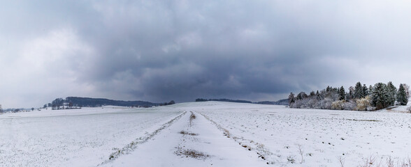 snowy field path with cloudy sky in Schmuttertal biotope near the village of Gablingen near Augsburg in Bavaria, Germany