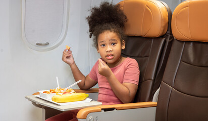6 year old girl A year old sits on a plane, eats a delicious spaghetti breakfast on the plane while flying abroad. 