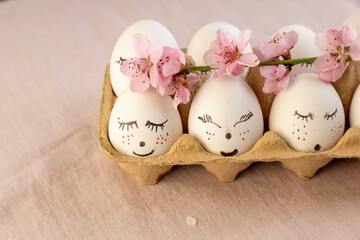 Natural white easter eggs with drawn sweet face in floral wreaths in a basket in soft light. Happy Easter, holiday card.