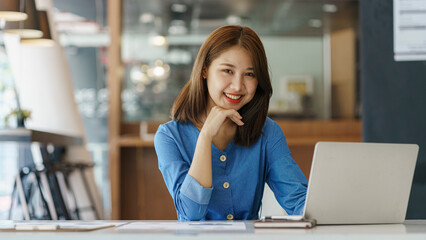Charming Asian Young woman freelancer working at the office using a laptop computer Looking at the...