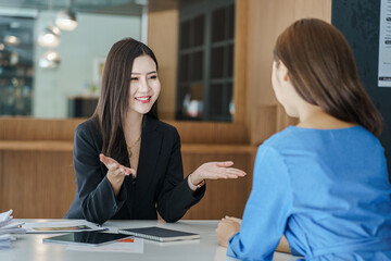 Two young attractive asian business woman in the conversation, exchanging ideas at work.