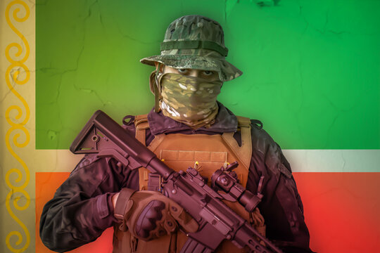 Angry chechens soldier armed with a rifle with a chechnya flag as background behind