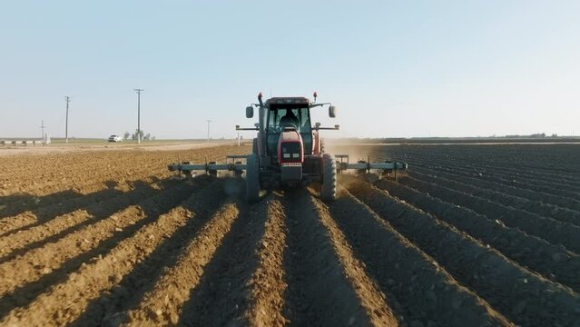 Aerial view of agricultural machinery loosening the soil before sowing seed. Big organic grain farmfield in rural area near the highway. High quality 4k footage