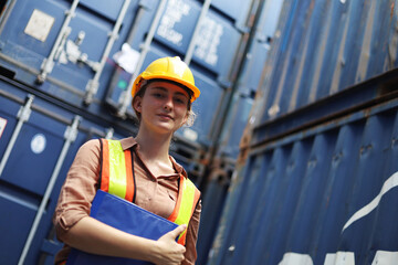 Young Engineers standing in the shipping yard tracking the cargo inventory and checking container box for safety.	