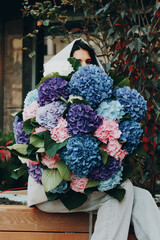 Beautiful huge colorful hydrangea monobouquet. Young woman holding hydrangea flowers of different colors.