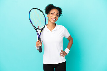 Young tennis player woman isolated on blue background posing with arms at hip and smiling