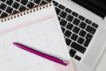Office desk with planner and pen on keyboard close-up.