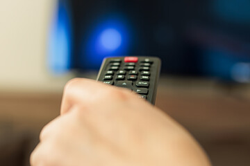 Woman hand with remote control on smart tv screen background.