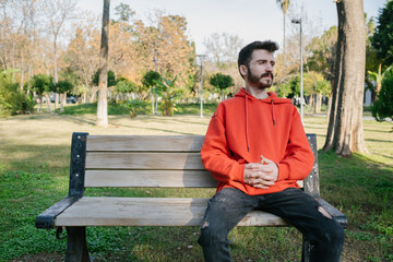 Man sitting on old park bench and looking away. Thinking, contemplation relaxing, concentration,...