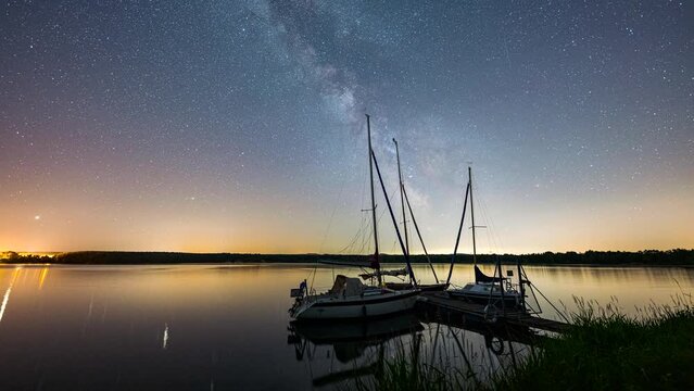 Zeitraffer der Milchstra&szlig;e an einem See mit drei Booten