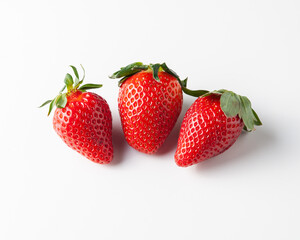 Three strawberries are on the table. On a white background.