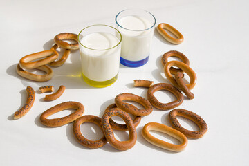 Fresh milk in glasses and bagels with poppy seeds on a table. 