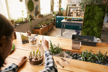 Female working in big studio, planting flowers