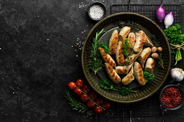 Grilled sausages with rosemary and spices. Barbecue. On a black stone background.