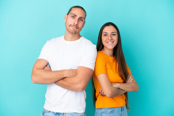 Fototapeta premium Young caucasian couple isolated on blue background keeping arms crossed