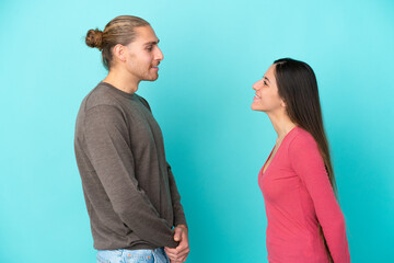 Young caucasian couple isolated on blue background with happy expression
