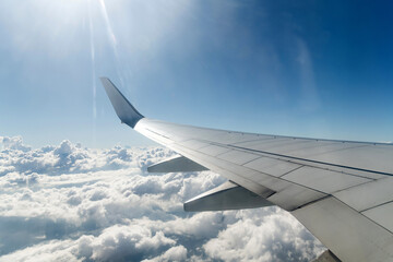 Fototapeta na wymiar Wing of airplane flying above clouds