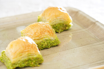 Pistachio baklava on a white wooden background. Baklava on a marble floor. Turkish baklava with pistachio, baklava slice