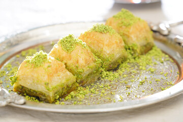 Pistachio baklava on a white wooden background. Baklava on a marble floor. Turkish baklava with pistachio, baklava slice