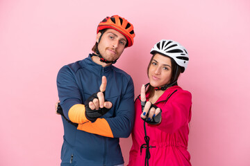Young cyclist caucasian people isolated on pink background showing and lifting a finger