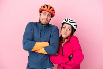 Young cyclist caucasian people isolated on pink background making doubts gesture while lifting the shoulders