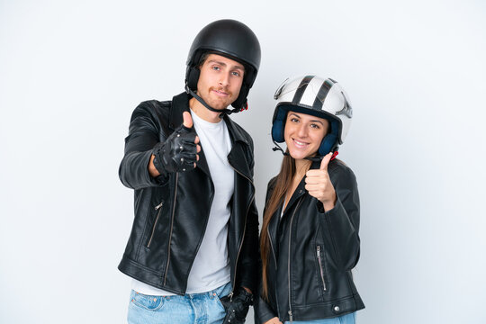 Young caucasian couple with a motorcycle helmet isolated on white background giving a thumbs up gesture because something good has happened