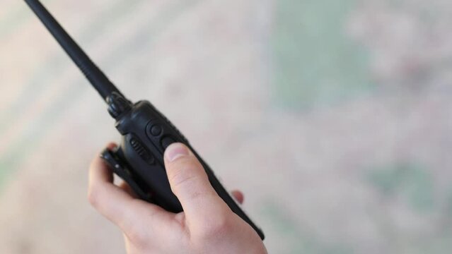 The man's hand uses a portable walkie-talkie on the background of the map. Slow motion video