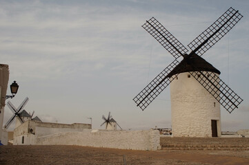 View of windmills among the typical white and blue streets of the municipality of Campo de Criptana (Ciudad Real) Spain.