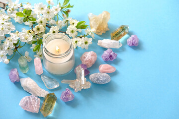 gemstones minerals, candle and flowers on blue background. Crystal ritual, Esoteric spiritual...