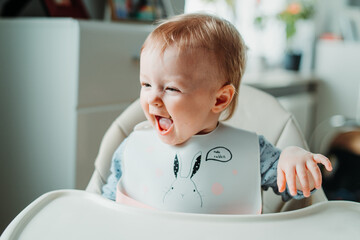 Baby girl sitting at the high chair and eating