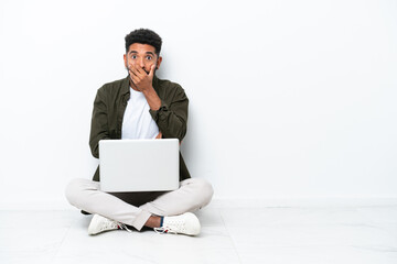 Young Brazilian man with a laptop sitting on the floor isolated on white surprised and shocked while looking right