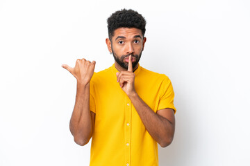 Young Brazilian man isolated on white background pointing to the side and doing silence gesture