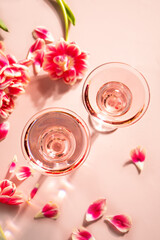 Glasses of pink cocktail with flowers and petals. Birthday party or Valentines day romatic couple concept.