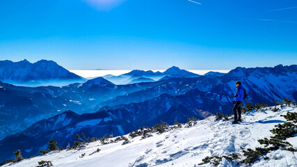 Active man snow shoe hiking on a trail with scenic view on snow capped mountain peaks of Karawanks in Carinthia, Austria. Ski tour. Julian Alps. Sunny winter day. Freedom. Winter wonderland, Hochobir