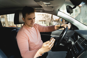 A one man talking on phone and looking at navigation in a car while driving 