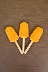 closeup the bunch orange color and flavor stick ice cream over out of focus brown background.