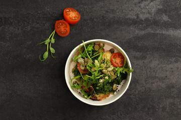 Fototapeta na wymiar Vegetarian salad with potato, tomatoes, arugula and pumpkin seeds in round paper take-away container on dark background. Healthy food delivery concept. Free space for text.