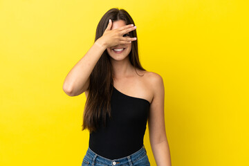 Young Brazilian woman isolated on yellow background covering eyes by hands and smiling