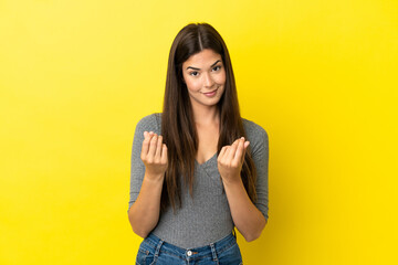 Young Brazilian woman isolated on yellow background making money gesture but is ruined
