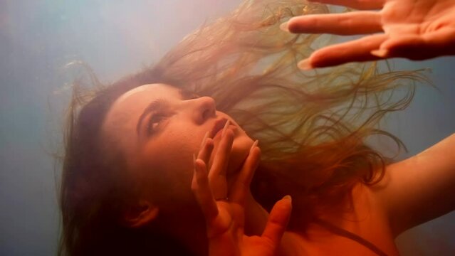 drowning into otherworld , closeup portrait of woman sinking in red water of pool or sea