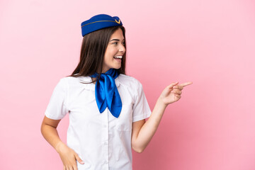 Airplane stewardess Brazilian woman isolated on pink background pointing finger to the side and presenting a product
